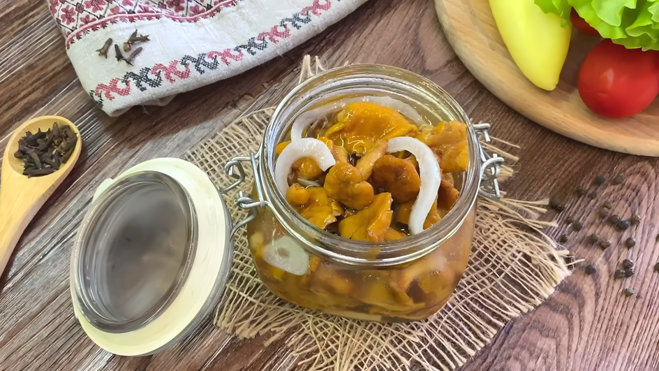 Открытая банка с маринованными лисичками и луком стоит на столе Открытая банка с маринованными лисичками и луком стоит на столе