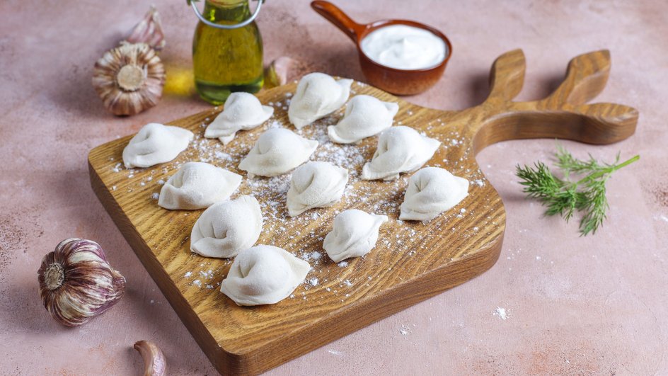 Пельмени с капустой и фаршем на деревянной доске Пельмени с капустой и фаршем на деревянной доске
