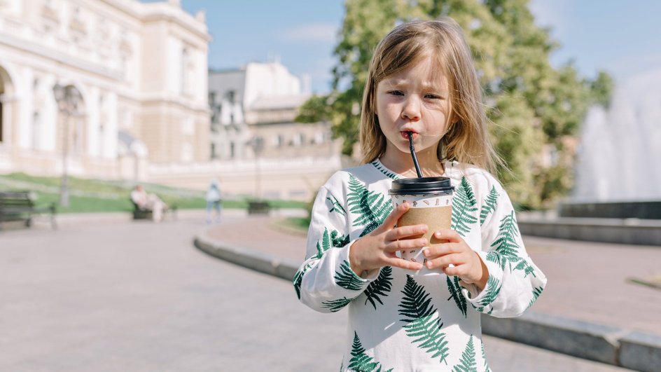 Девочка пьет кофе из стаканчика на улице