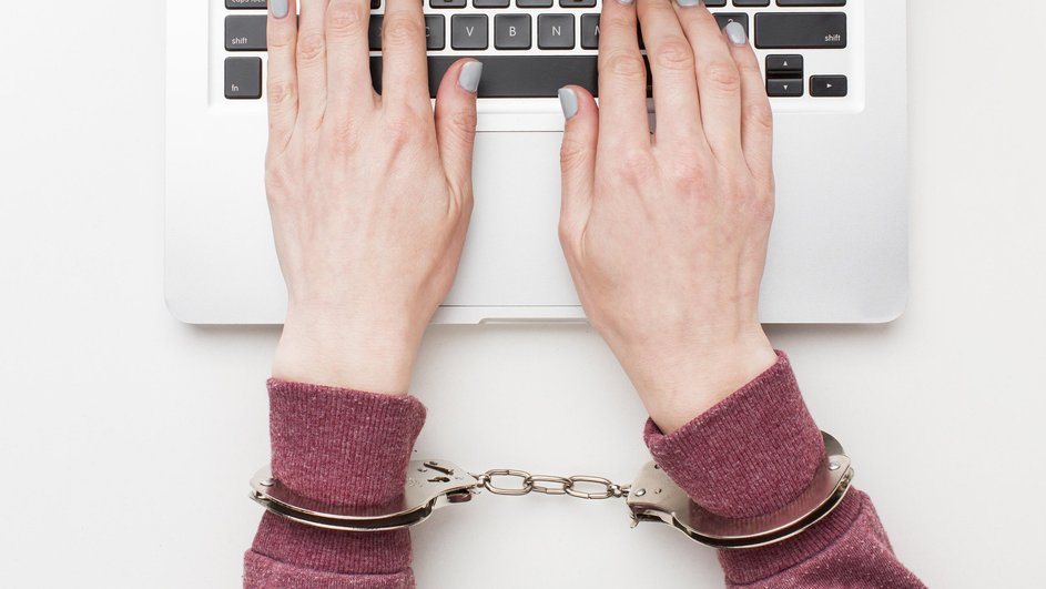 Женщина в наручниках работает на ноутбуке Женщина в наручниках работает на ноутбуке