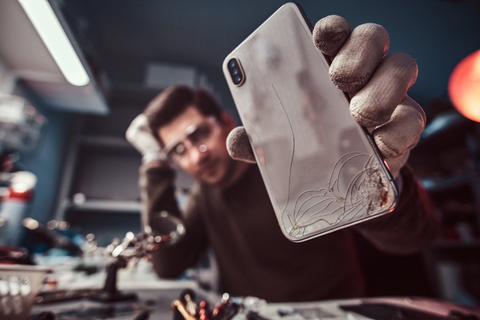 Разбитый смартфон в руках у мастера ремонта