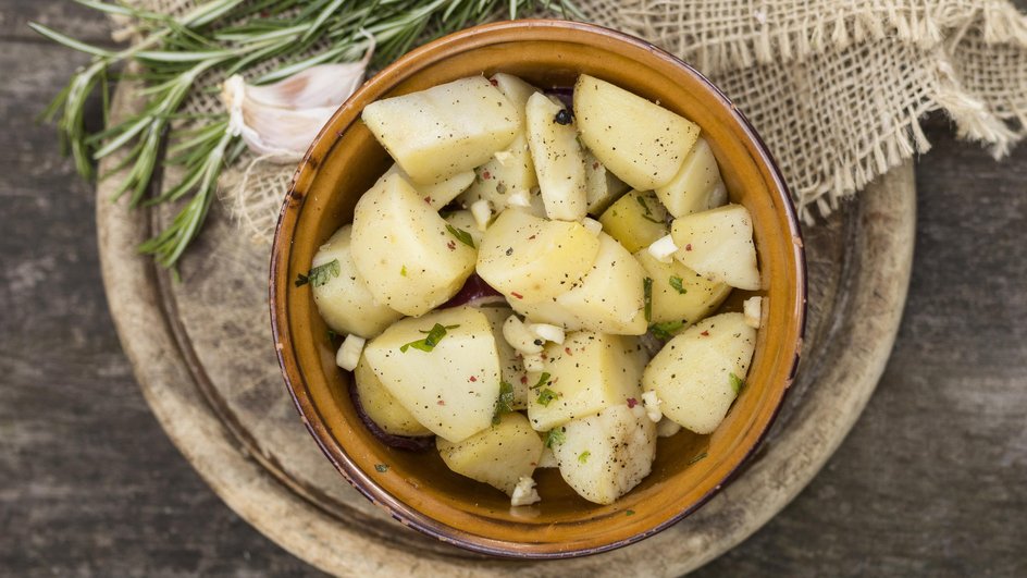 Рагу из картошки и капусты, приготовленное в кастрюле, лежит в глубокой тарелке