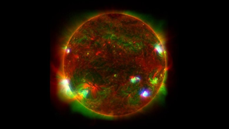Комбинированное фото Солнца состоит из наложенных друг на друга 25 изображений. Синие точки соответствует высокоэнергетическому рентгеновскому излучению, зеленые — низкоэнергетическому, а красные — ультрафиолетовому. Фото: NASA/JPL-Caltech/JAXA