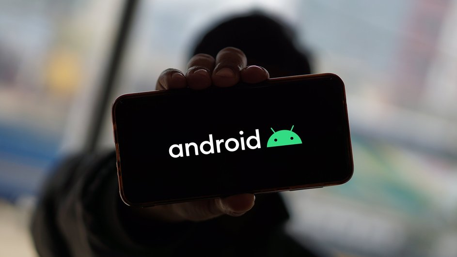 Парень держит в руке телефон на Android, на котором горит иконка Android