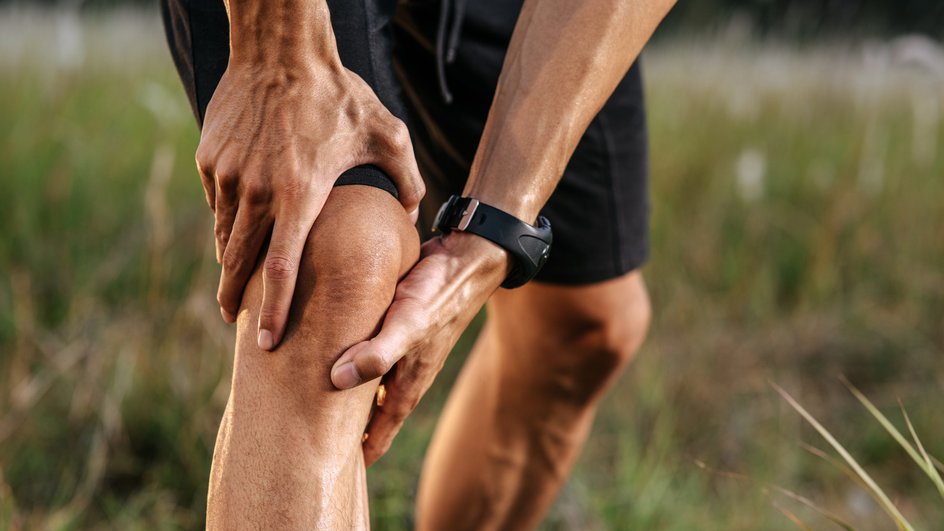 Спортсмен испытывает боль в колене Спортсмен испытывает боль в колене