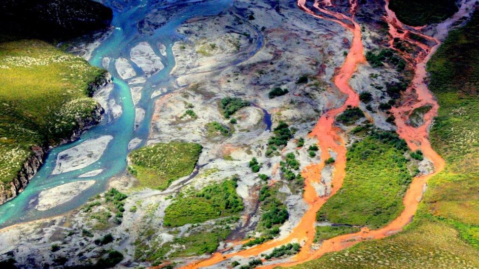 Вид с воздуха на ржавую реку Кутук в национальном парке «Ворота Арктики» на Аляске. Таяние вечной мерзлоты подвергает минералы выветриванию, повышая кислотность воды, в результате чего выделяются такие металлы, как железо, цинк и медь. Фото: Кен Хилл / Служба национальных парков.