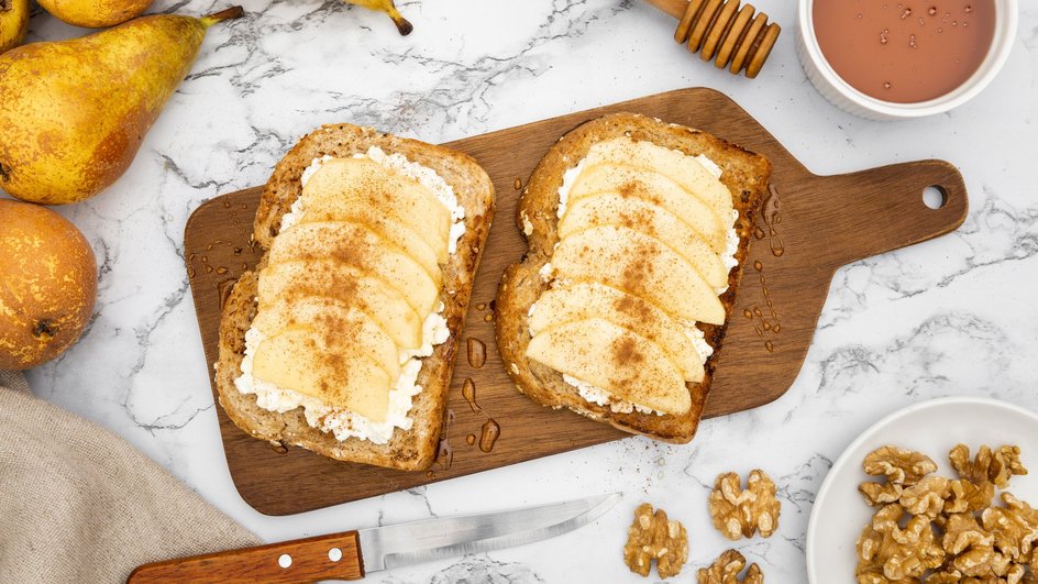 Мягкие сладкие гренки лежат на доске рядом с грушей и орехами