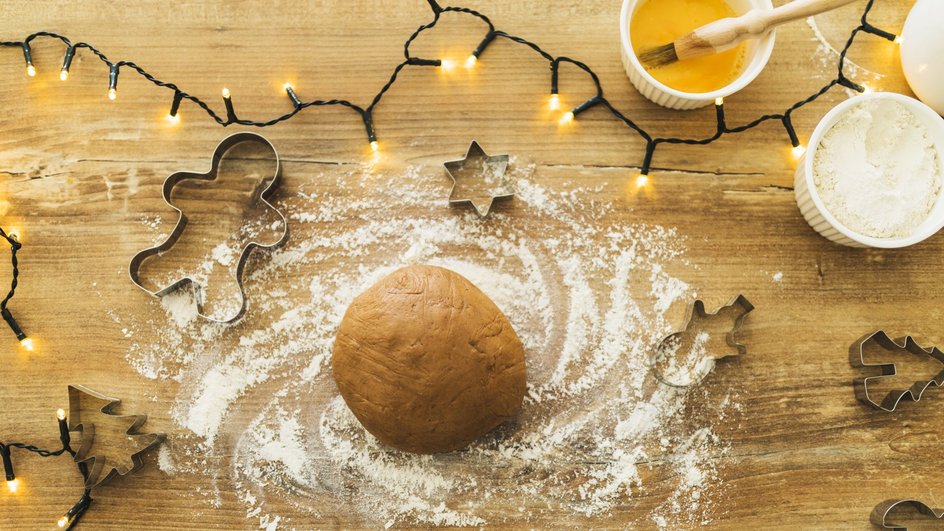 Сырое тесто для медовых пряников лежит на столе рядом с формочками и ингредиентами Сырое тесто для медовых пряников лежит на столе рядом с формочками и ингредиентами
