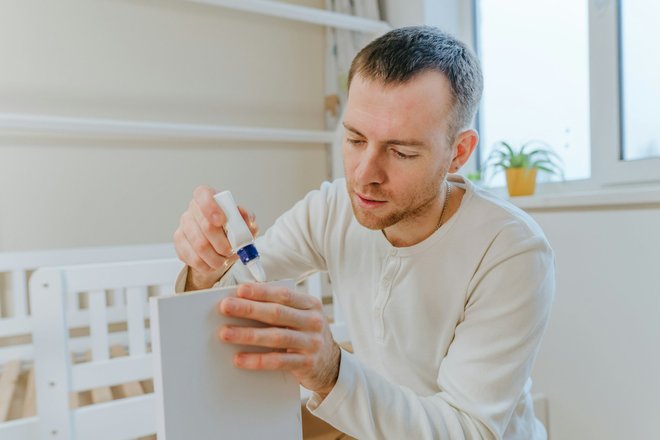 young-man-using-glue-for-fixing-the-drawer-of-bed-in-the-kids-bedroom young-man-using-glue-for-fixing-the-drawer-of-bed-in-the-kids-bedroom