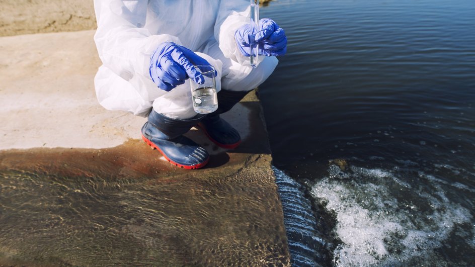 ученый берет пробу воды