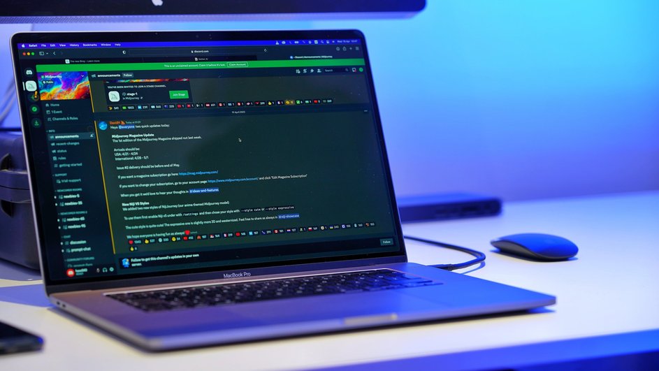 Приложение Discord открыто на экране ноутбука, стоящего рядом с компьютерной беспроводной мышью на столе