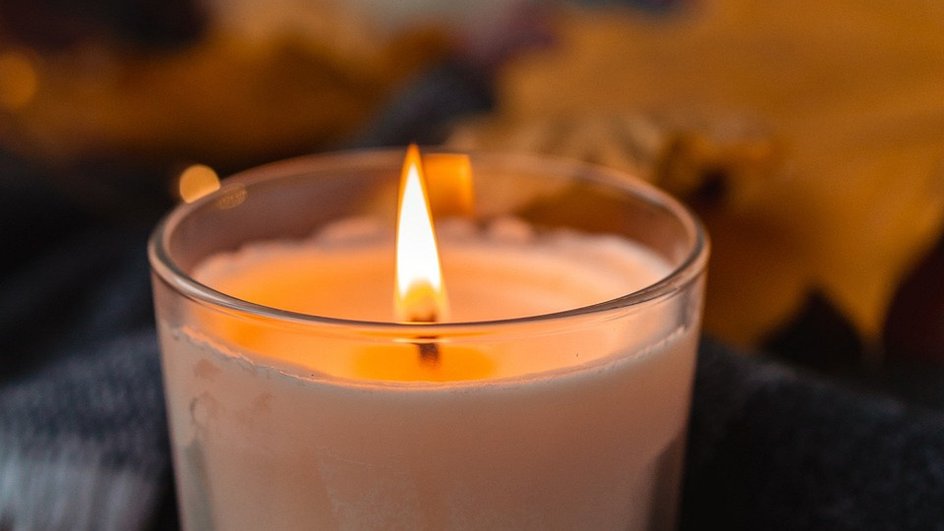 Белая горящая свеча в прозрачном стакане 