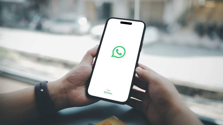 Парень держит в руках телефон, на котором загружается приложение WhatsApp