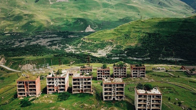 Недостроенные дома в поселке Кани, Кармадонское ущелье, Северная Осетия-Алания. На заднем плане: остатки сошедшего ледника Колка