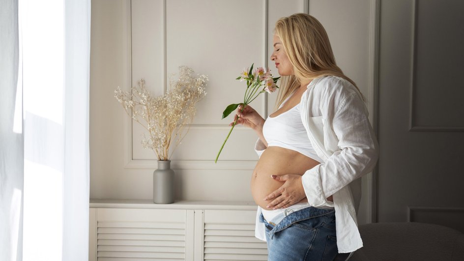 Беременная женщина вдыхает аромат цветов