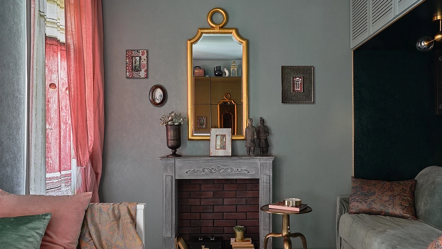 Зеркало в золотой раме висит за зеленой стене в гостиной 
