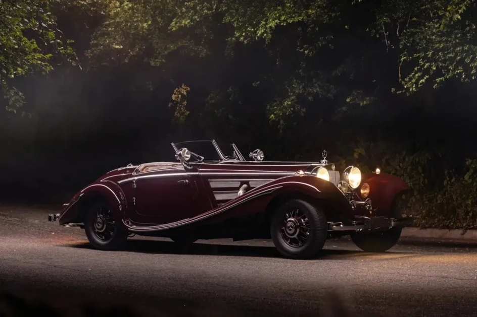 Вечером бордовый Mercedes-Benz 500 K Special Roadster с включенными фарами выглядит роскошно